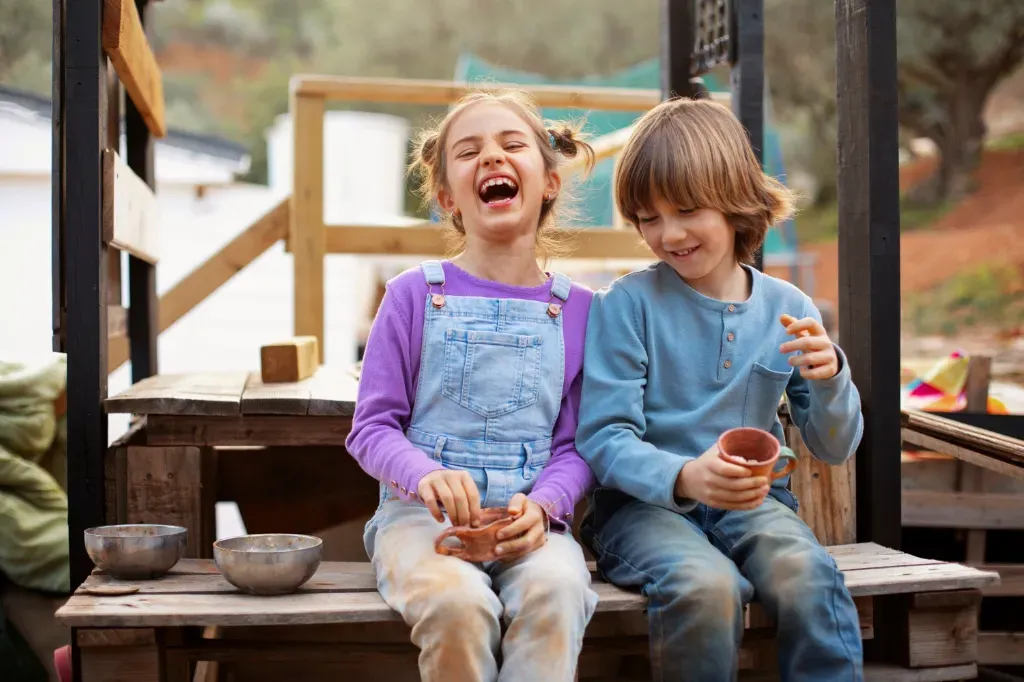 dziewczynka i chłopiec śmieją się i siedzą obok siebie na ławce